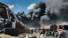 FILE - People are seen in front of clouds of black smoke from fires in the aftermath at the scene of an airstrike in Mekele, the capital of the Tigray region of northern Ethiopia on Oct. 20, 2021.