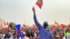 Comício da UNITA - Um homem ergue uma pequena bandeira do partido no meio da multidão. Cazenga, Luanda, Angola