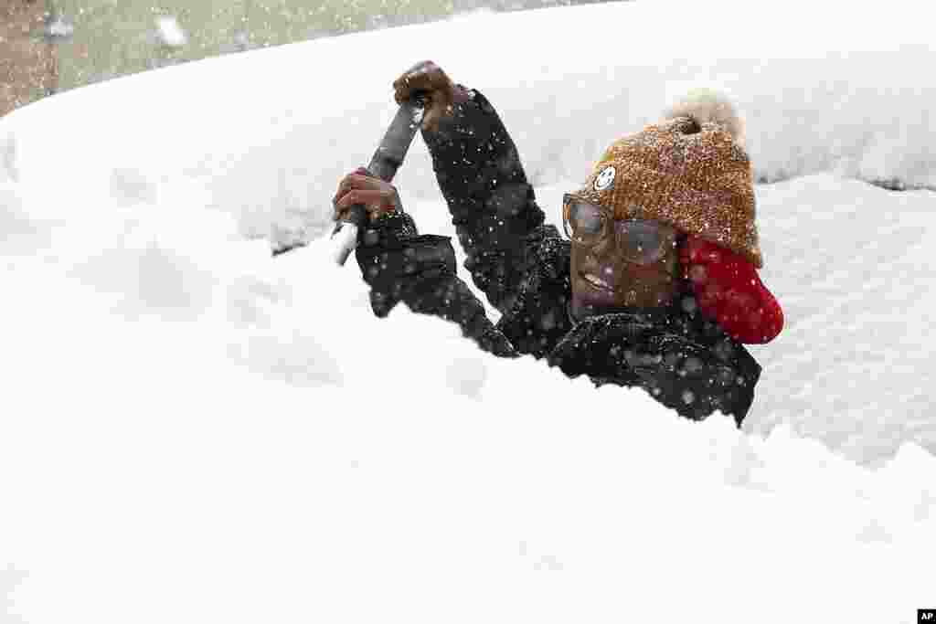 Zaria Black, 24, , clears off her car as snow falls in Buffalo, N.Y.