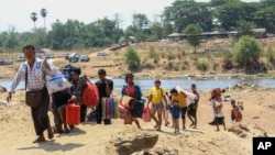 FILE - People cross the Moei river as they flee Myawaddy township in Myanmar to Thailand's Mae Sot town in Thailand's Tak province, April 20, 2024. 