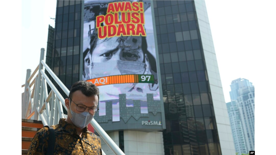A man walks on a bridge past a billboard that says "Beware of Air Pollution" at the main business district in Jakarta, Indonesia, on Oct. 3, 2023.
