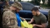 Ukraine's President Volodymyr Zelenskyy signs a national flag for a service member at a petrol station after visiting positions near the front line in Donetsk region on June 26, 2023. (Ukrainian Presidential Press Service/via Reuters)