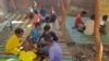Children share a large bowl of food, as Sudanese families host internally displaced people coming from the central Sudanese state of Gezira to the eastern Sudanese city of Gedaref, June 3, 2024.