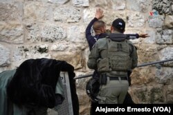 Un policía israelí cachea a un joven palestino en la Puerta de los Leones, uno de los accesos a la Ciudad Vieja de Jerusalén, por donde transitan miles de musulmanes que se dirigen a orar en la Explanada de las Mezquitas.