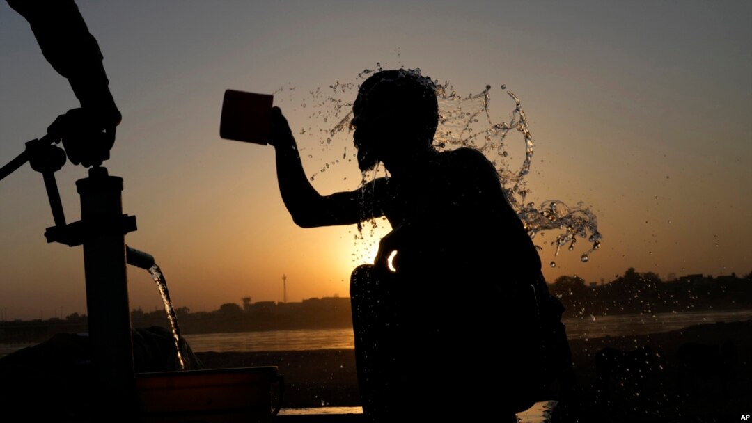 A youth cools off under a hand pump at the sunset during hot weather in Lahore, Pakistan, May 28, 2024. 