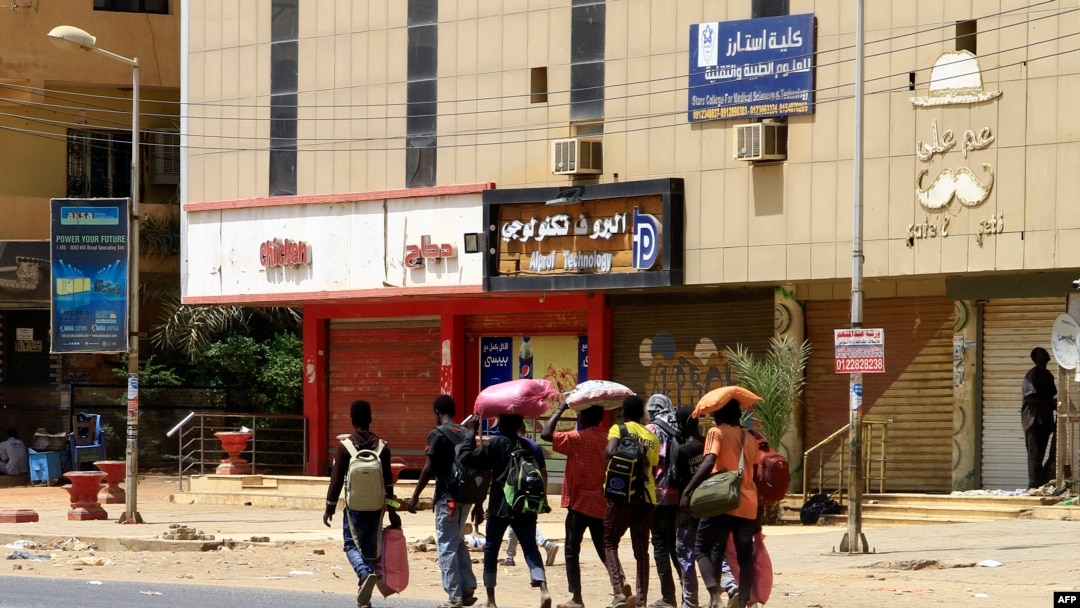 Watu wakiwa wamebeba mali zao, wakitembea kando kando ya barabara huko Khartoum, tarehe 16 Aprili 2023. Picha na Shirika la habari la AFP.