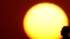 FILE - A woman is silhouetted against the setting sun as triple-digit heat indexes continue in the Midwest, Aug. 20, 2023, in Kansas City, Missouri. 
