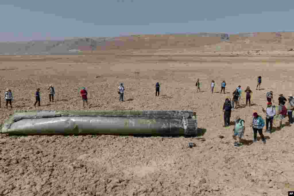 People gather around a component from an intercepted ballistic missile that fell near the Dead Sea in Israel, April 20, 2024.