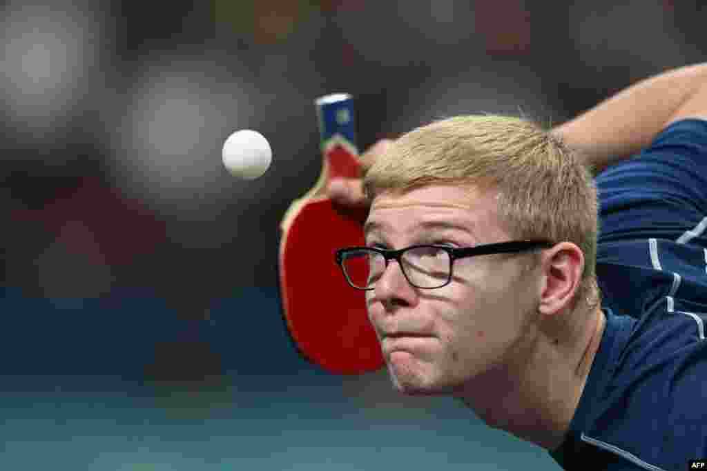 France's Felix Lebrun eyes the ball while serving during his men's table tennis singles match in the team semifinal between China and France at the Paris 2024 Olympic Games at the South Paris Arena in Paris.