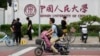北京街頭人們經過中國人民大學校園外牆的標誌。 （2024年7月22日）