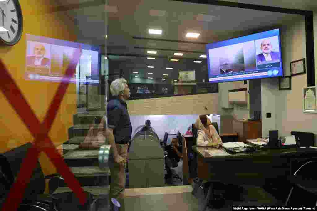 People follow the news of a crash of a helicopter carrying Iran's President Ebrahim Raisi, on a TV in a shop in Tehran. A helicopter carrying Iranian President Ebrahim Raisi and his foreign minister crashed as it was crossing mountain terrain in heavy fog, an Iranian official told Reuters, and rescuers were struggling to reach the site of the incident.