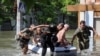 Police evacuate local residents from a flooded area in Kherson on June 7, 2023, after the Nova Kakhovka dam breached the previous day amid Russia's attack on Ukraine. (Ivan Antypenko/Reuters)