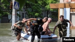 Police evacuate local residents from a flooded area in Kherson on June 7, 2023, after the Nova Kakhovka dam breached the previous day amid Russia's attack on Ukraine. (Ivan Antypenko/Reuters)