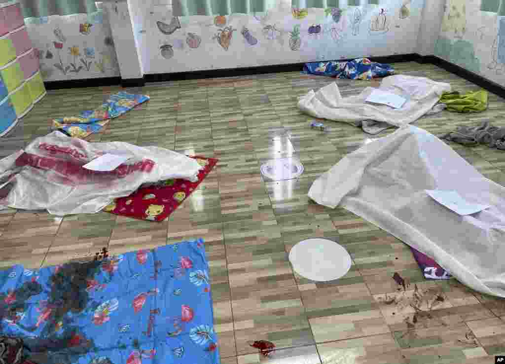 Sheets cover the bodies of young victims at the site of an attack in a day care center in the town of Nongbua Lamphu, north eastern Thailand. A former policeman facing a drug charge burst into the day care center, killing at least 37 people including 22 children.