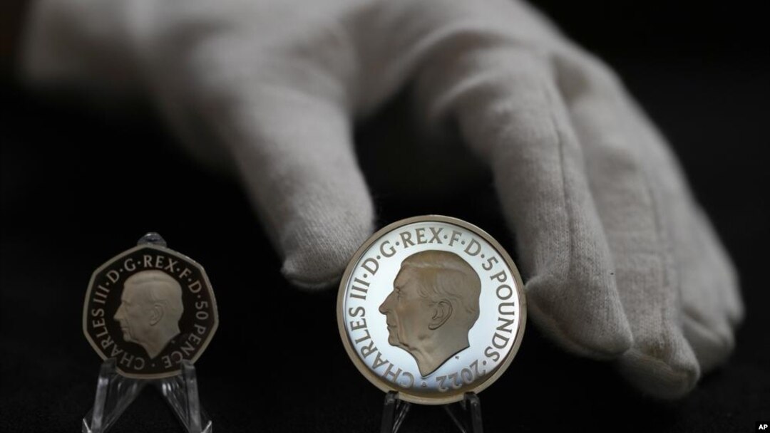 Dos monedas nuevas muestran el retrato oficial del rey Carlos III: una de 50 peniques a la izquierda y una de 5 libras a la derecha, en Londres, el jueves 29 de septiembre de 2022. (AP Foto/Alastair Grant)