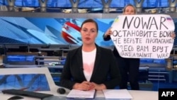 This video grab taken on March 15, 2022, shows Russian Channel One editor Marina Ovsyannikova holding a poster that reads "Stop the war. Don't believe the propaganda. Here, they are lying to you." (AFP)