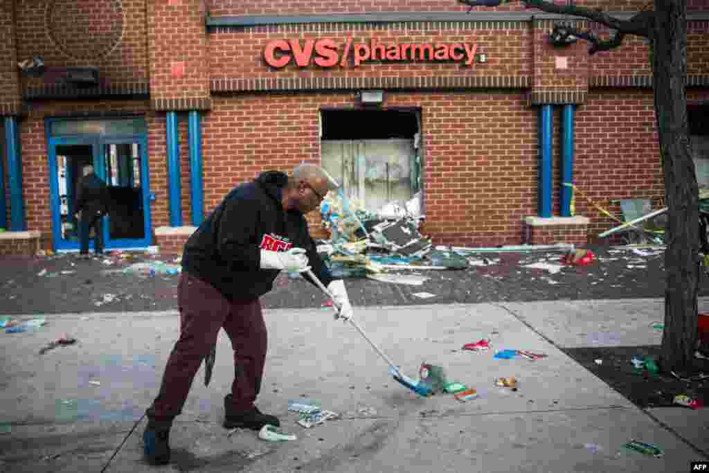 Jerald Miller helps clean up debris from a CVS pharmacy that was set on fire yesterday during rioting after the funeral of Freddie Gray, on April 28, 2015 in Baltimore, Maryland.
