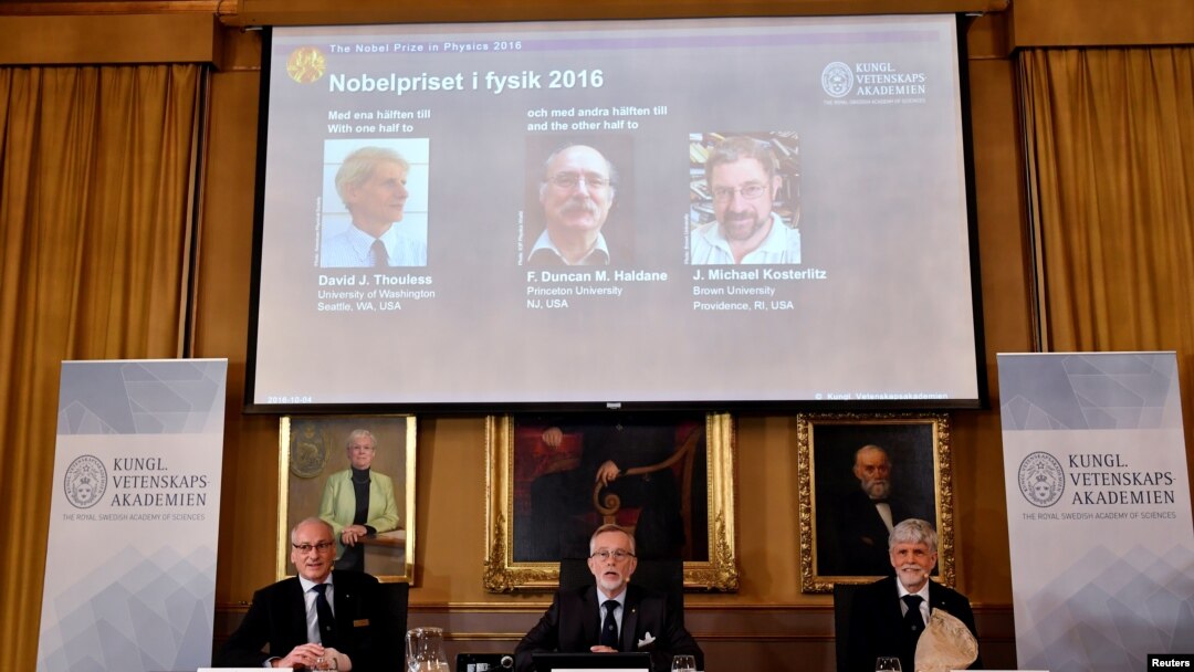 Les membres de l'Académie royale des sciences Nils Martensson, Goran K Hansson et Thomas Hans Hansson, sont assis sous la photographie des prix Nobel David Thouless, Duncan Haldane and Michael Kosterlitz, à Stockholm, Suède, le 4 octobre 2016.