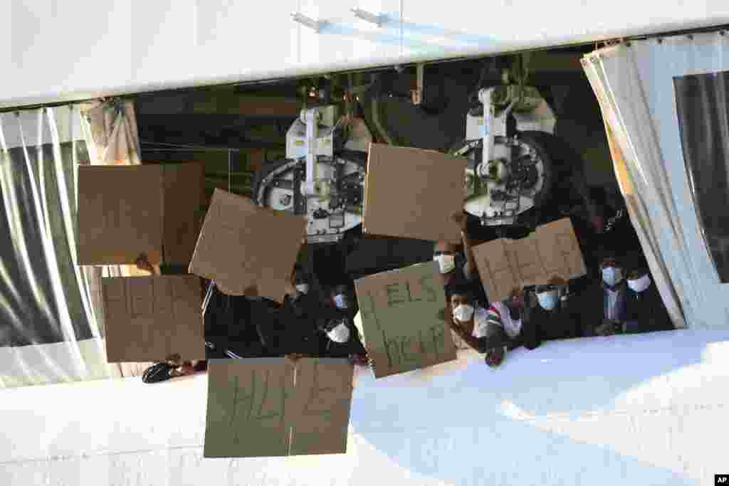 Migrants hold banners asking for help, from a deck of the Norway-flagged Geo Barents ship operated by Doctors Without Borders, in Catania's port, Sicily, southern Italy. The Geo Barents has been allowed to disembark 357 migrant that Italian authorities defined as "vulnerable people" and minors, while leaving another 215 people that were declared non-vulnerable blocked on board. 