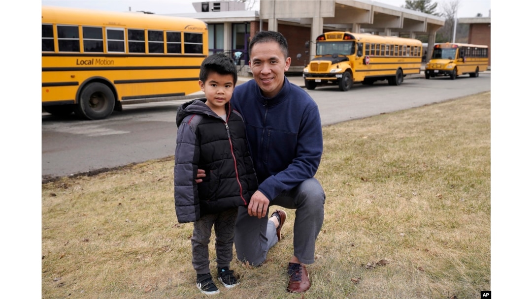 Jason Chan, right, kneels next to his 5-year-old son Skyler, both of Needham, Mass. (AP Photo/Steven Senne)