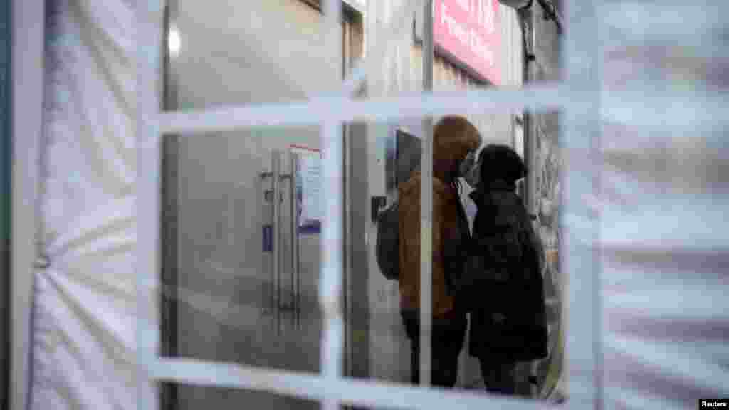A couple wearing protective masks kiss at a hospital's fever clinic as COVID-19 outbreaks continue in Shanghai.