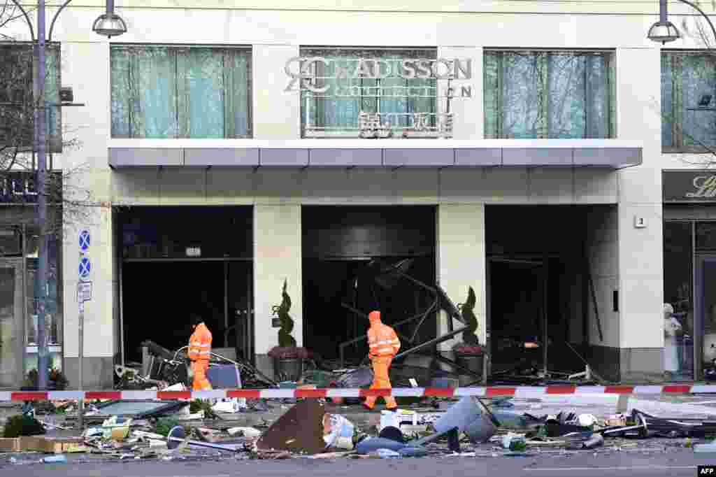 Workers of the city cleaning department walk past debris covering the street in front of the Radisson Blu hotel in Berlin after a 14-meter-high aquarium in the hotel's lobby burst, forcing the closure of a nearby street, police and firefighters said.
