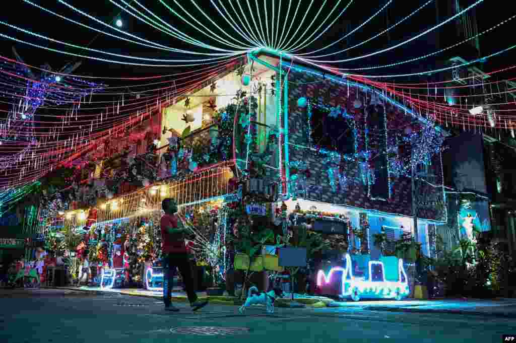 A man walks with a dog past a Christmas-themed house in Manila, Philippines, Dec. 21, 2022.