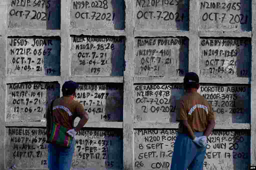 Prison inmates look at tombs during a mass burial of 70 unclaimed bodies of prisoners at New Bilibid Prison Cemetery in Muntinlupa, metro Manila, Philippines.
