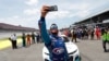 El conductor Bubba Wallace se se hace un autorretrato con su teléfono junto a sus compañeros, quienes empujaron su auto al frente de la Pista Talladega antes del inicio de la carrera de autos de la Copa NASCAR el 22 de junio de 2020.