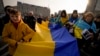 People carry a large Ukrainian flag during a protest against Russia's war on Ukraine, marking the first anniversary of Russia's full-scale, in Bucharest, Romania, on February 24, 2023. (Andreea Alexandru/AP) 