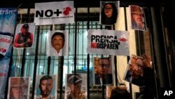 FILE - A woman posts photos of murdered journalists during a protest against the murder of journalists Lourdes Maldonado and Margarito Martínez in Mexico City, Jan. 25, 2022. Mexico ranks as one of the most dangerous places in the world to practice journalism outside a war zone.