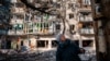 A woman stands in front of a residential building damaged by Russian shelling in Kherson, Ukraine on December 20, 2022. (Photo by Dimitar Dilkoff/AFP)