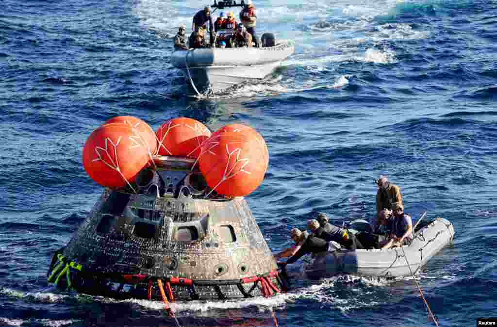 U.S. Navy divers secure NASA's Orion Capsule after it splashed down, Dec. 11, 2022, following a successful uncrewed Artemis I moon mission, seen from aboard the U.S.S. Portland in the Pacific Ocean off the coast of Baja California, Mexico.