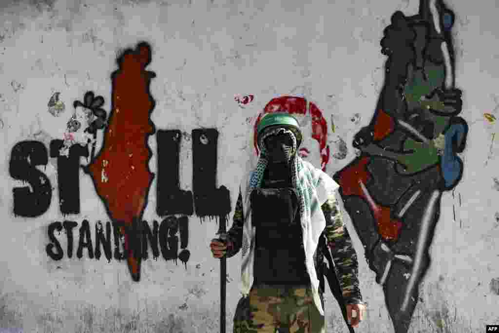 A masked supporter of the Hamas movement takes part in a rally in the West Bank village of Beit Omar, to mark the 35th anniversary of the Palestinian militant group.