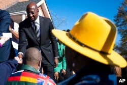 Sen. Raphael Warnock, D-Ga., shakes hands at a rally before walking to cast his early vote Nov. 27, 2022, in Atlanta, in his runoff election against Republican Herschel Walker.