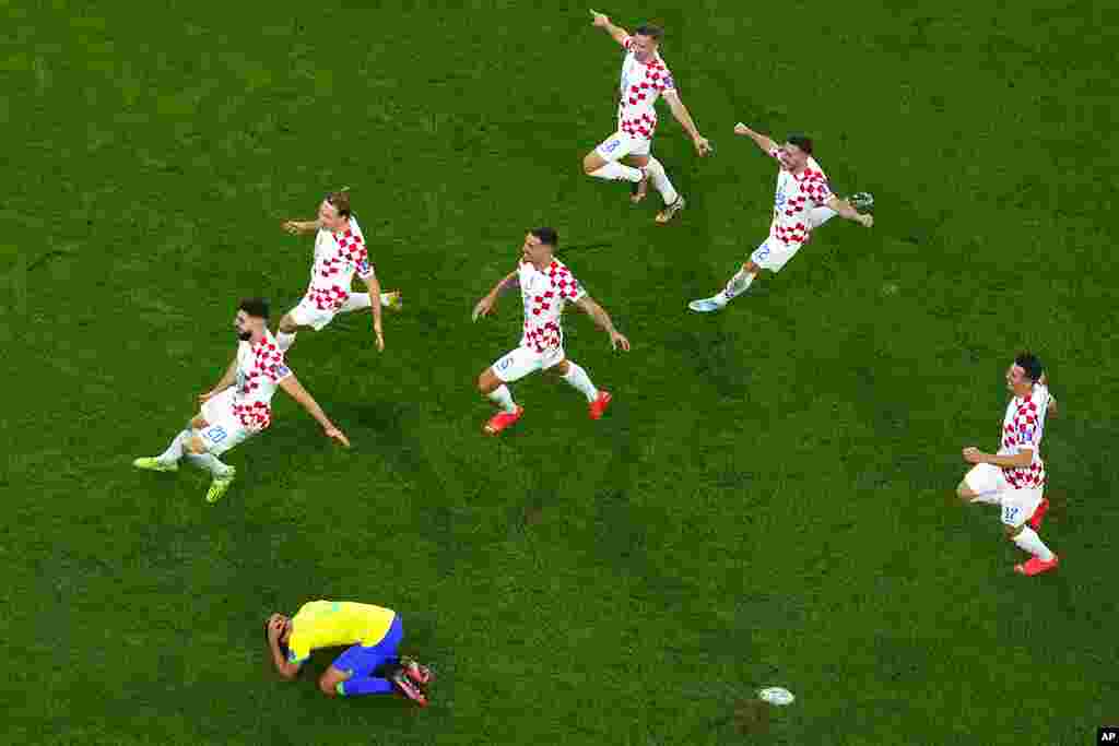 Brazil's Marquinhos is dejected after failing to score from the penalty spot as Croatia's players celebrate winning the World Cup quarterfinal soccer match between Croatia and Brazil, at the Education City Stadium in Al Rayyan, Qatar.