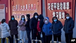 北京市民在宣傳習近平思想的標語牆前排隊等候接受核酸檢測。（2022年12月5日）