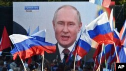 People in Sevastopol, Crimea, watch on a large screen on September 30, 2022, as Russian President Vladimir Putin delivers a speech after Moscow carried out sham referendums to justify annexing four regions of Ukraine. (Associated Press)