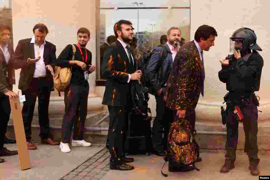 Real estate firm workers participating in The District real estate fair, speak to the police after activists threw colored powder on them during a protest denouncing the housing crisis and evictions, in Barcelona, Spain, Oct. 19, 2022.