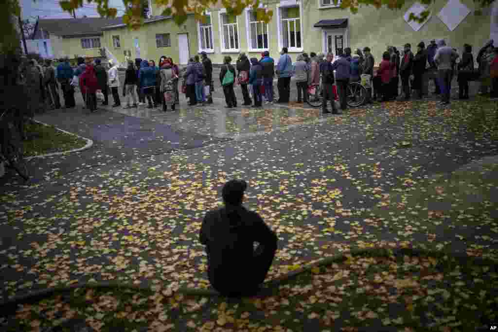 People queue to receive a daily ration of bread in a school in Mykolaiv, Ukraine. One person is allowed to receive free bread just once in three days. 