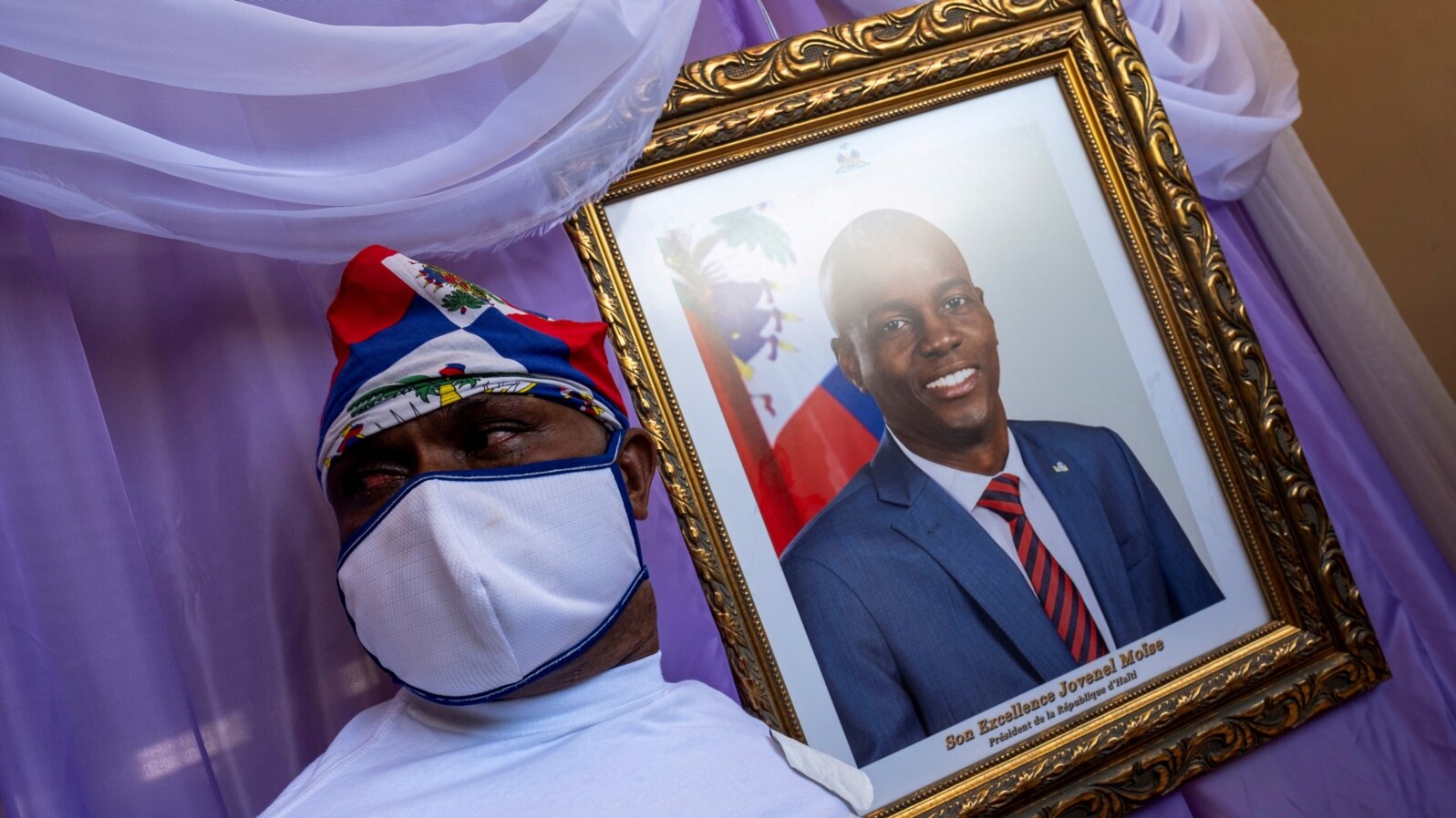 A man stands next to a portrait of slain Haitian President Jovenel Moise placed on a memorial at the city hall in Cap-Haitien, Aug. 22, 2021.