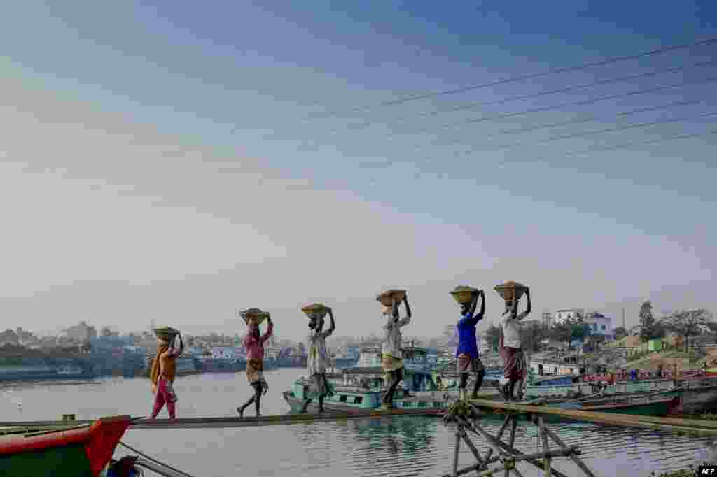 Laborers unload building materials from a cargo ship in Gabtoli, on the outskirts of Dhaka, Bangladesh.