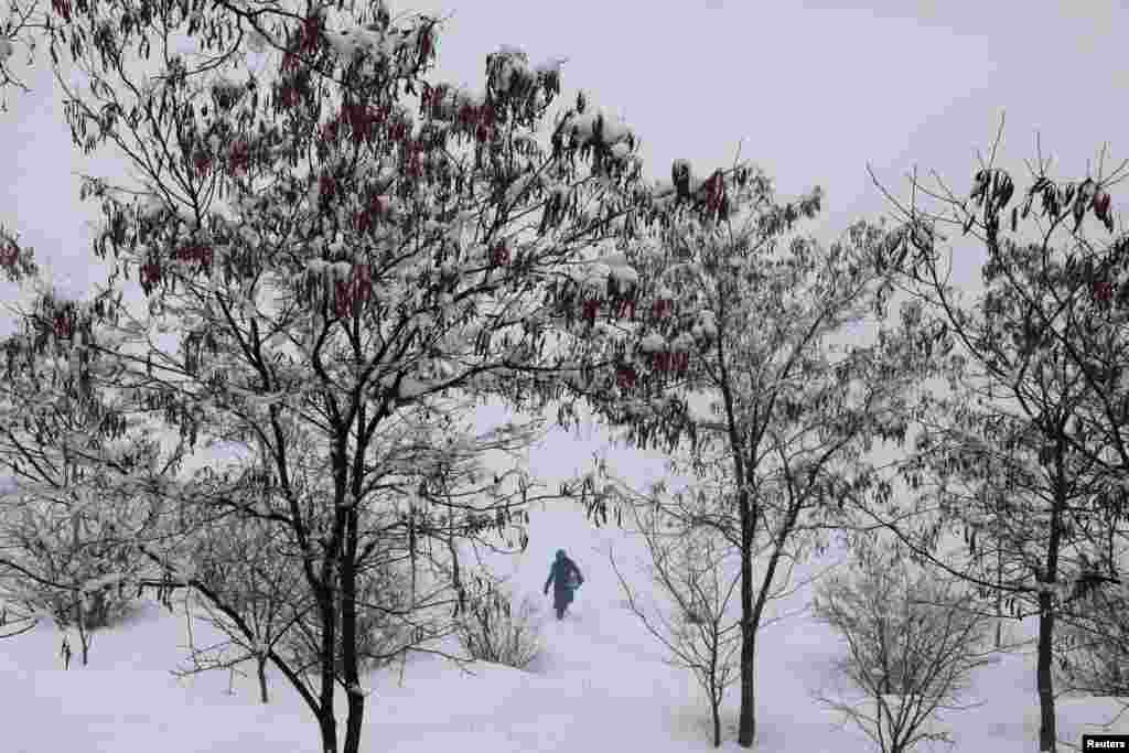 A woman walks on the snow-covered ground on a snowy day in Kabul, Afghanistan.