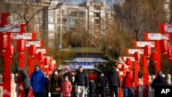 Visitors walk across a bridge decorated with lanterns at a public park in Beijing on the first day of the Lunar New Year holiday, Jan. 22, 2023.