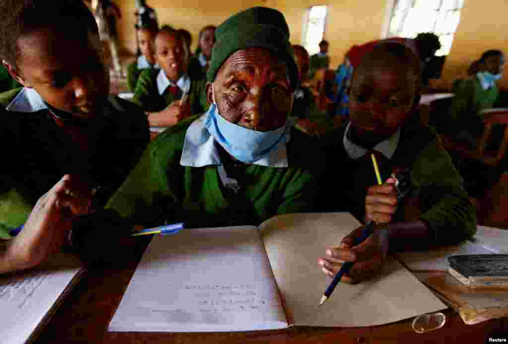 Priscilla Sitienei, a 98-year-old primary school student in grade six, is helped to do an assignment by her classmates at the Leaders Vision Preparatory School in Ndalat village of Nandi County, Kenya, Jan. 25, 2022.