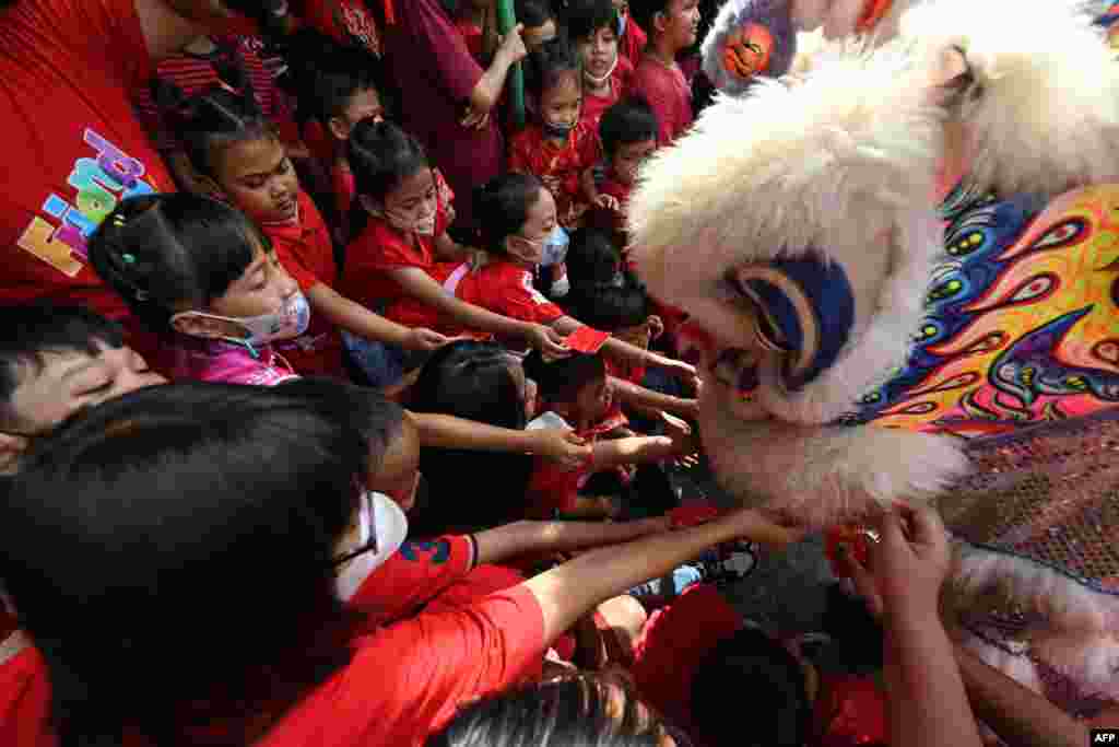 Children give money to lion dance performers at a school as part of festivities to welcome the upcoming Lunar New Year of the Rabbit in Solo, Central Java, Indonesia.