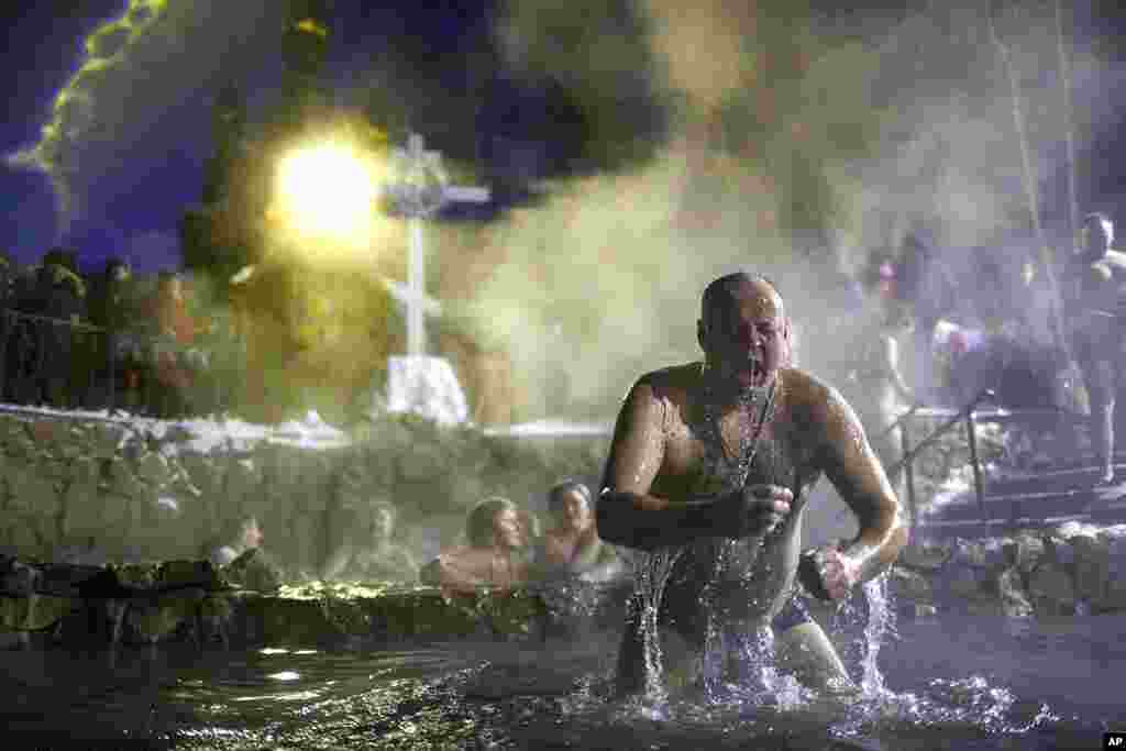 A man bathes in water during a traditional Epiphany celebration as the temperature dropped to about -12 degrees (10.4 degrees Fahrenheit) near the Achairsky monastery outside the Siberian city of Omsk, Russia.