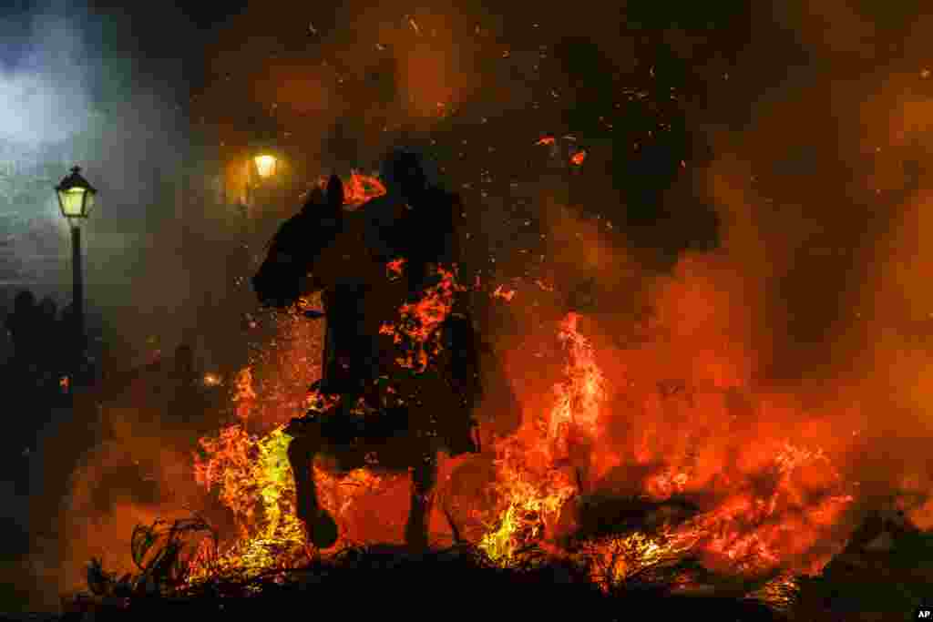 A man rides a horse through a bonfire as part of a ritual in honor of Saint Anthony the Abbot, the patron saint of domestic animals, in San Bartolome de Pinares, Spain, Jan. 16, 2023.