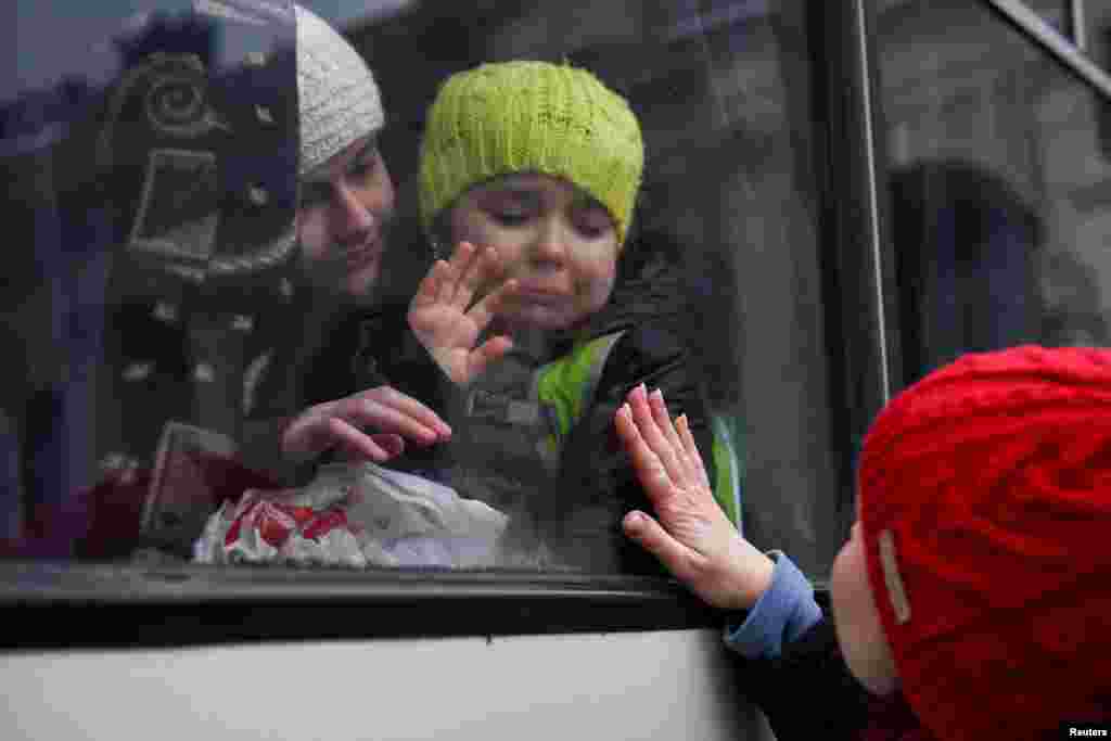 Alexandra, 12, holds her sister Esyea, 6, who cries as she waves at her mother Irina, while members of the Jewish community of Odessa board a bus to flee Russia's invasion of Ukraine, in Odessa, Ukraine.