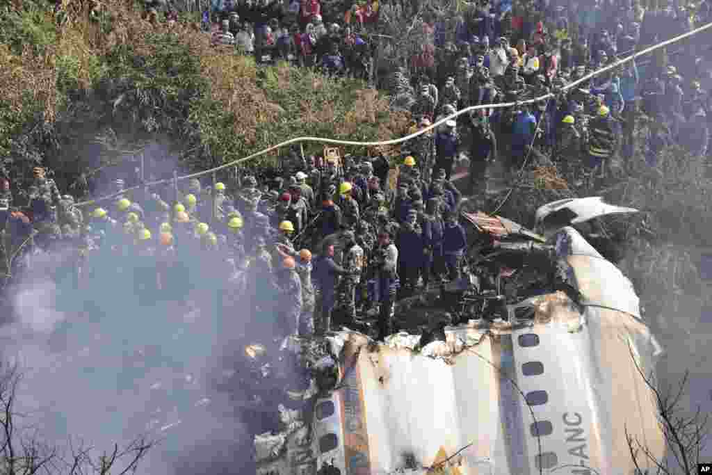 Rescue workers and civilians gather around the wreckage of a passenger plane that crashed in Pokhara, Nepal. Authorities said 68 people have been confirmed dead after a regional passenger plane with 72 aboard crashed into a gorge while landing at a newly opened airport in the resort town of Pokhara.